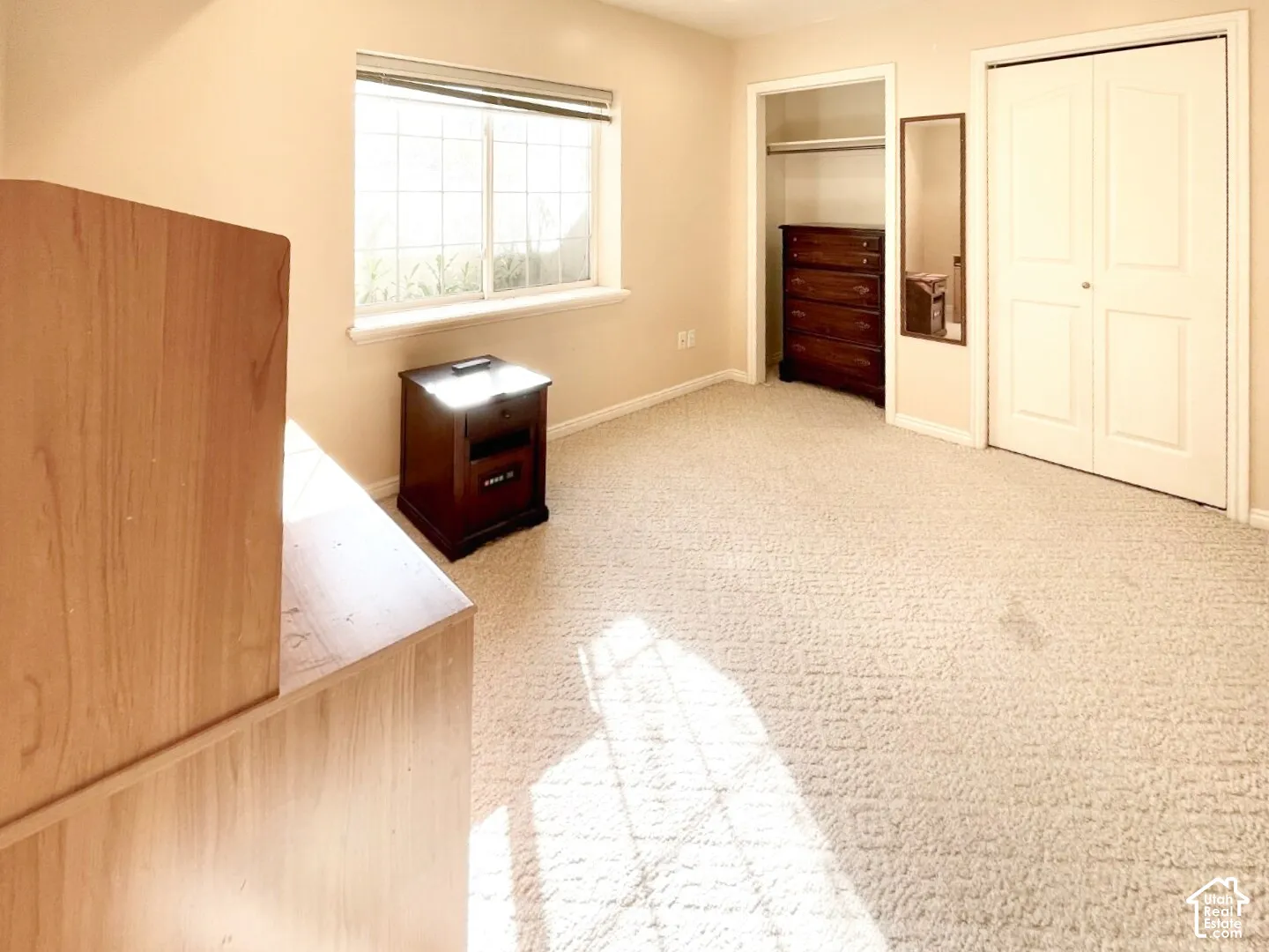 Neutral-toned carpeting, sliding double closet doors, walk-in closet space, and a grid-pane window