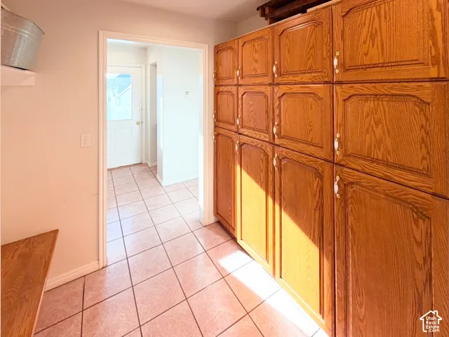 Wall-to-wall wood cabinetry with brass hardware, ceramic tile flooring, and an integrated wood bench surface
