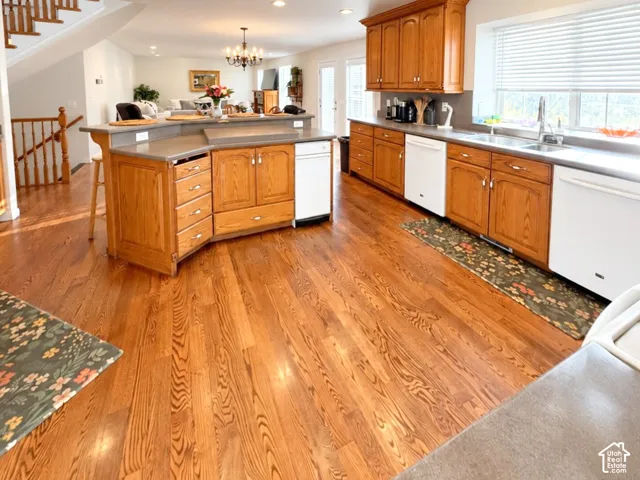 Kitchen featuring wood-finish flooring, oak cabinetry, solid-surface countertops, and a multi-level island with integrated seating