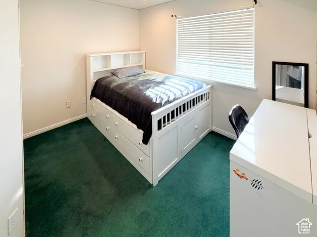 Neutral interior space featuring carpeted flooring and a horizontal window with attached blinds