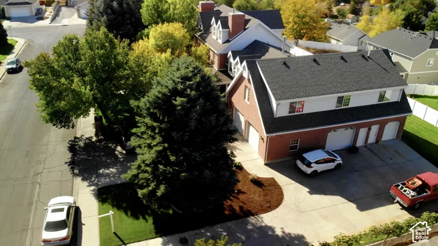 Multi-level brick exterior with a pitched roof, dormer windows, attached multi-car garage, and concrete driveway