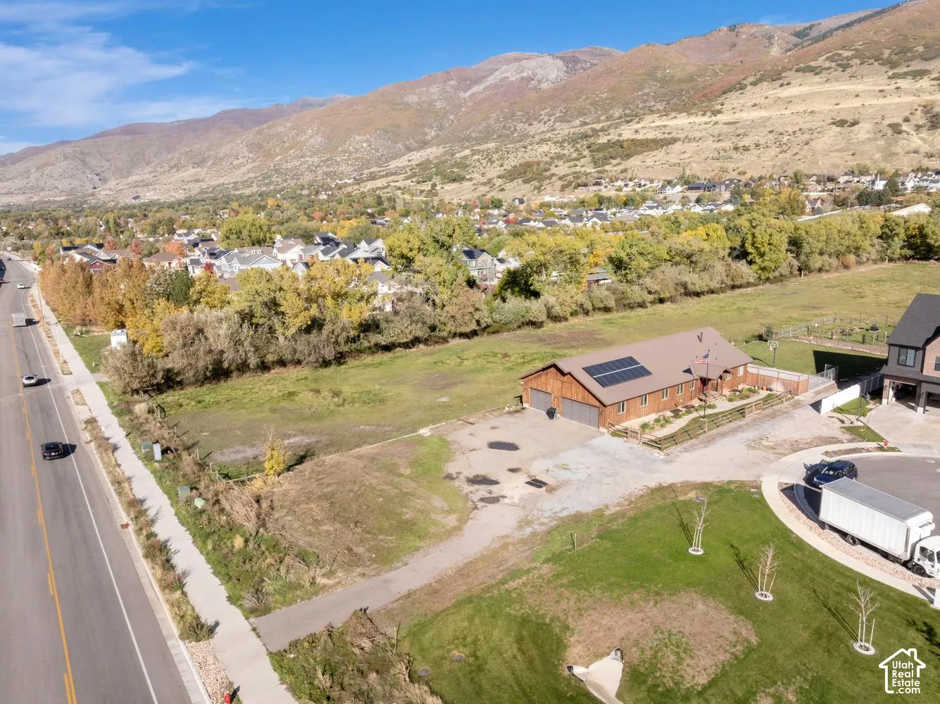 Single-story residence featuring a wood-sided exterior, attached multi-car garage, roof-mounted solar panels, and sprawling lot with mountain backdrop