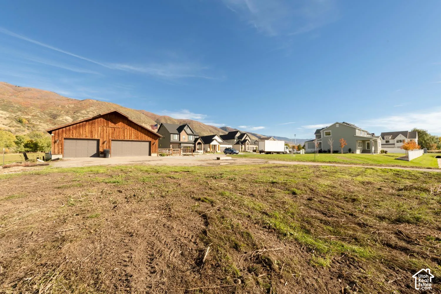 Expansive lot featuring a wood-sided detached garage with dual doors and a backdrop of mountain scenery