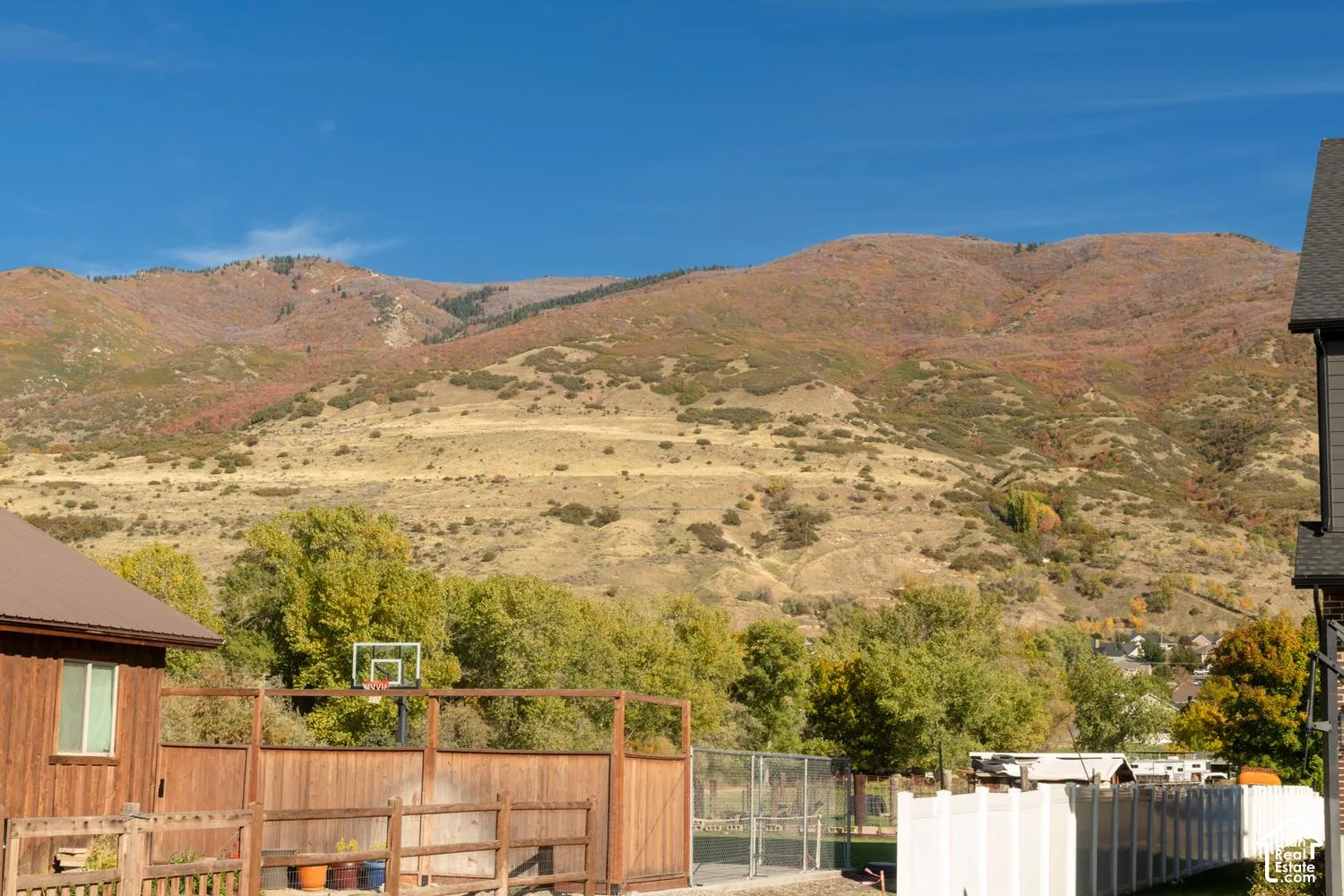 Expansive exterior grounds featuring mountain backdrop, vertical wood siding, custom wood fencing, and metal roofing