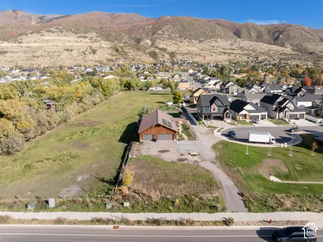 Expansive lot featuring a detached wood-sided garage, asphalt driveway, and mountain backdrop