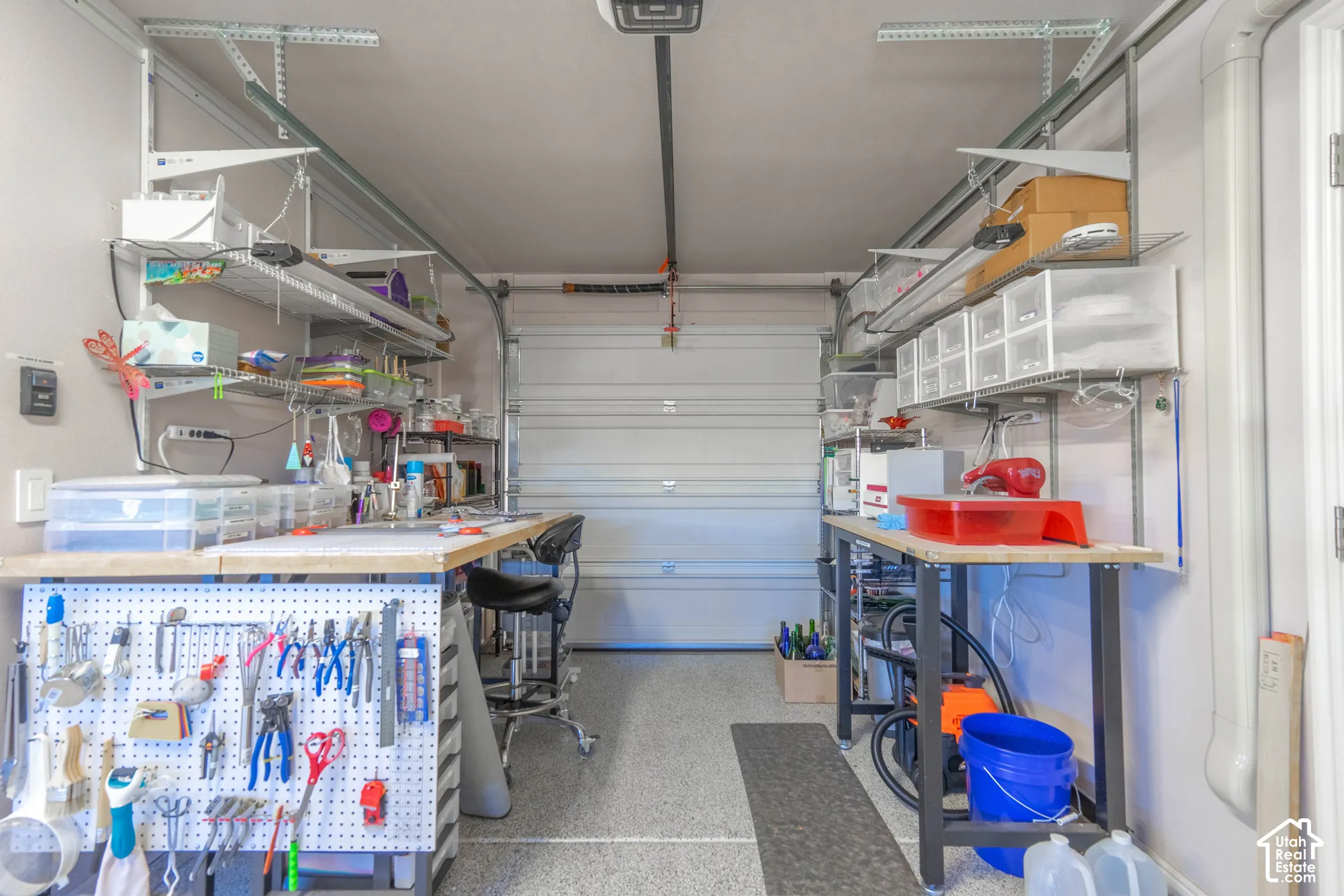 Extra length in Garage, interior featuring an epoxy-coated floor, integrated wall-mounted storage shelving, and built-in pegboard organization systems. Extra Roll Up Door into Back Yard