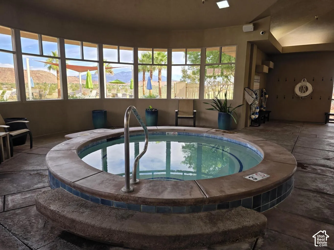 Circular indoor spa featuring tile surround, integrated concrete bench seating, stainless steel handrail, and expansive window wall with mountain scenery