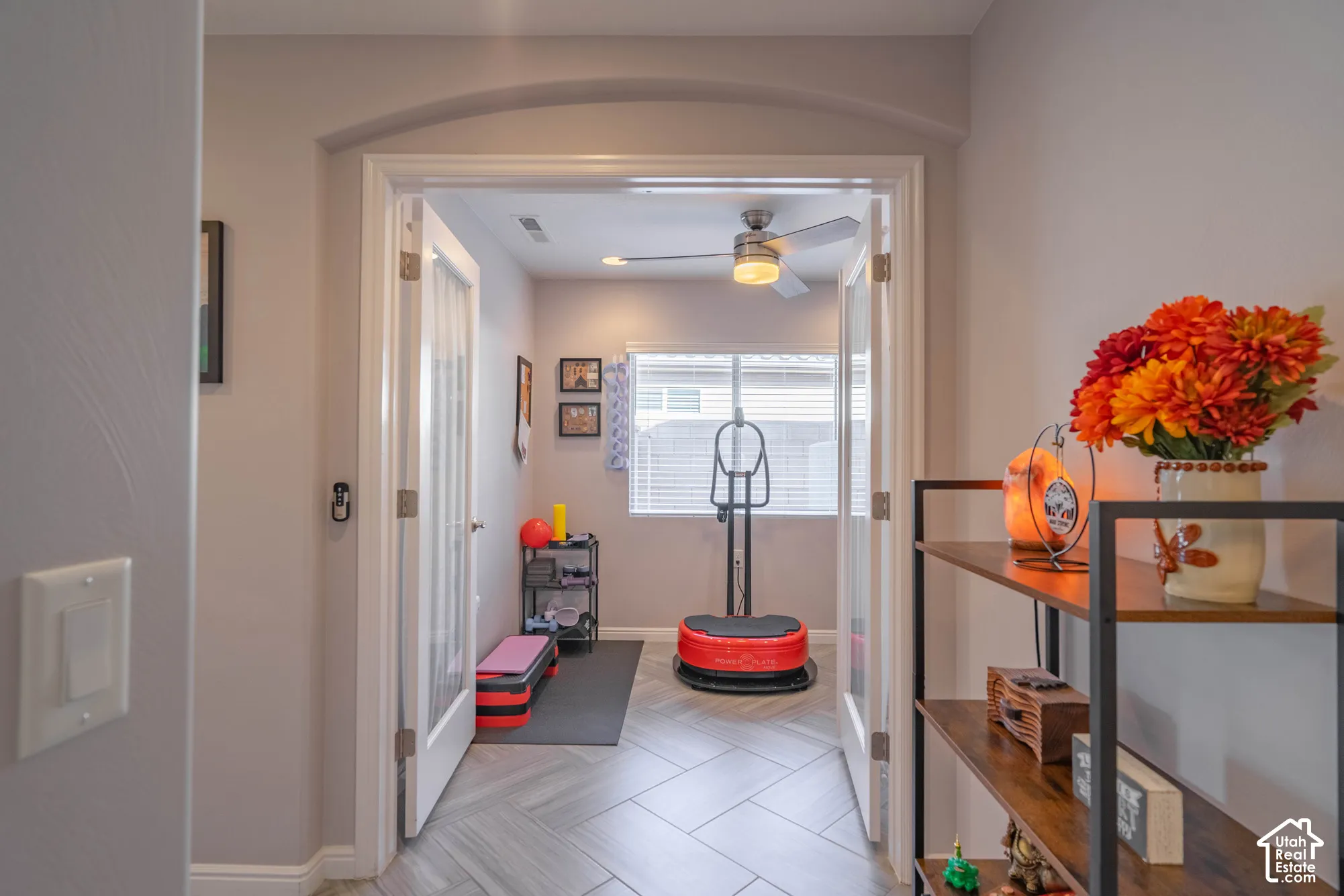 Room featuring double French doors with glass panels, arched entry header, herringbone-patterned tile flooring, and a ceiling fan with integrated lighting