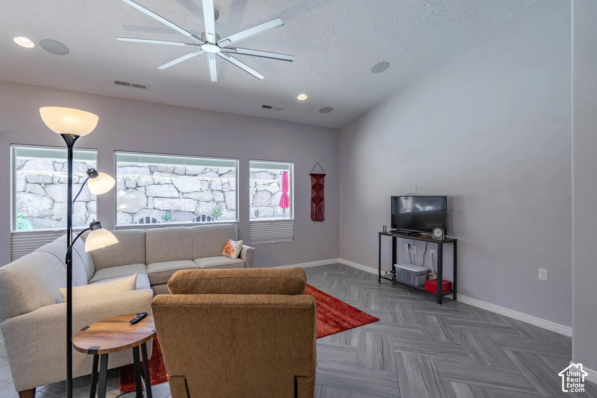Vaulted ceilings with a multi-blade LED ceiling fan, herringbone-patterned tile flooring, recessed lighting, and expansive windows