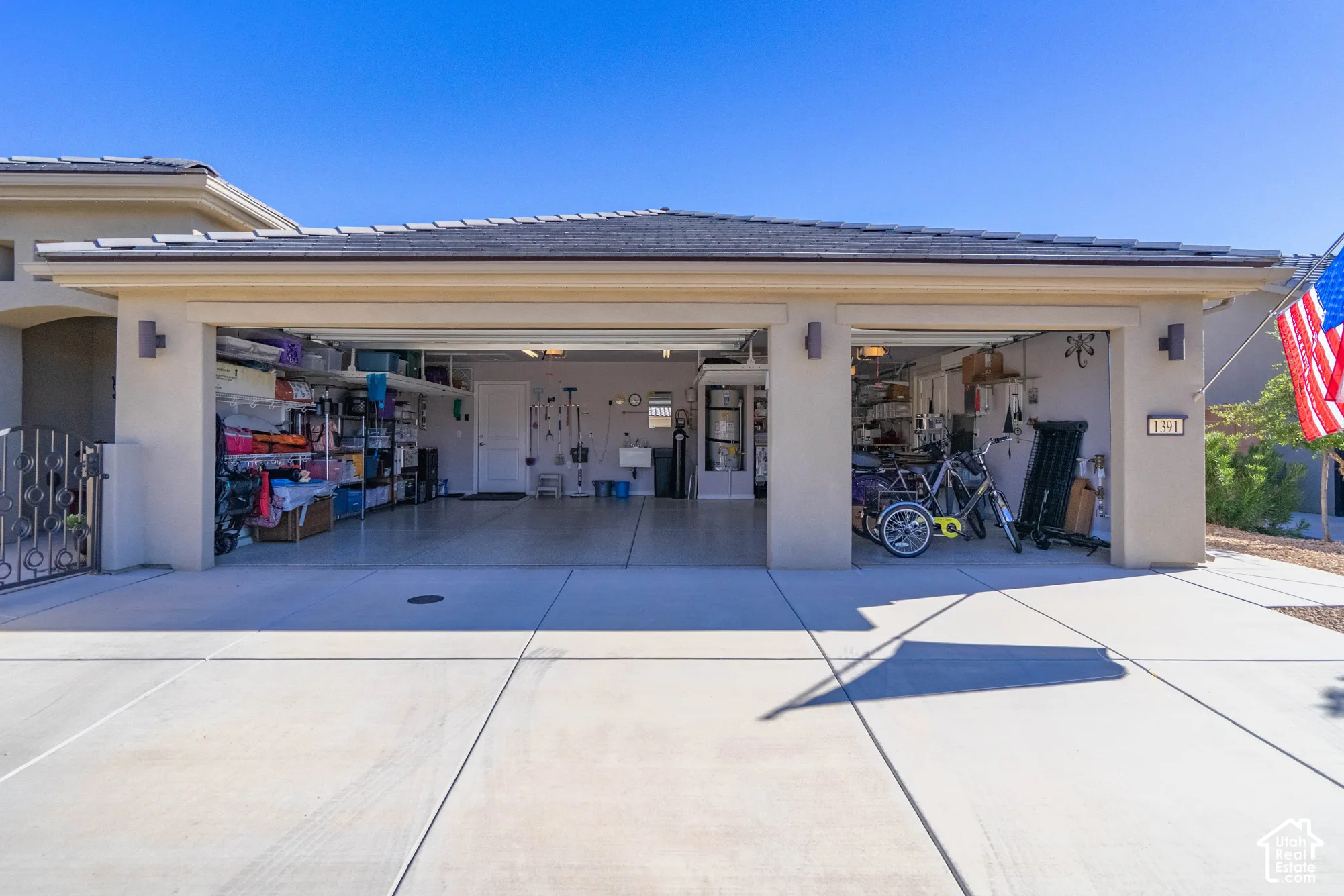 Three-and-a-half-car garage featuring a concrete driveway, dual-entry doors, and wall-mounted exterior lighting