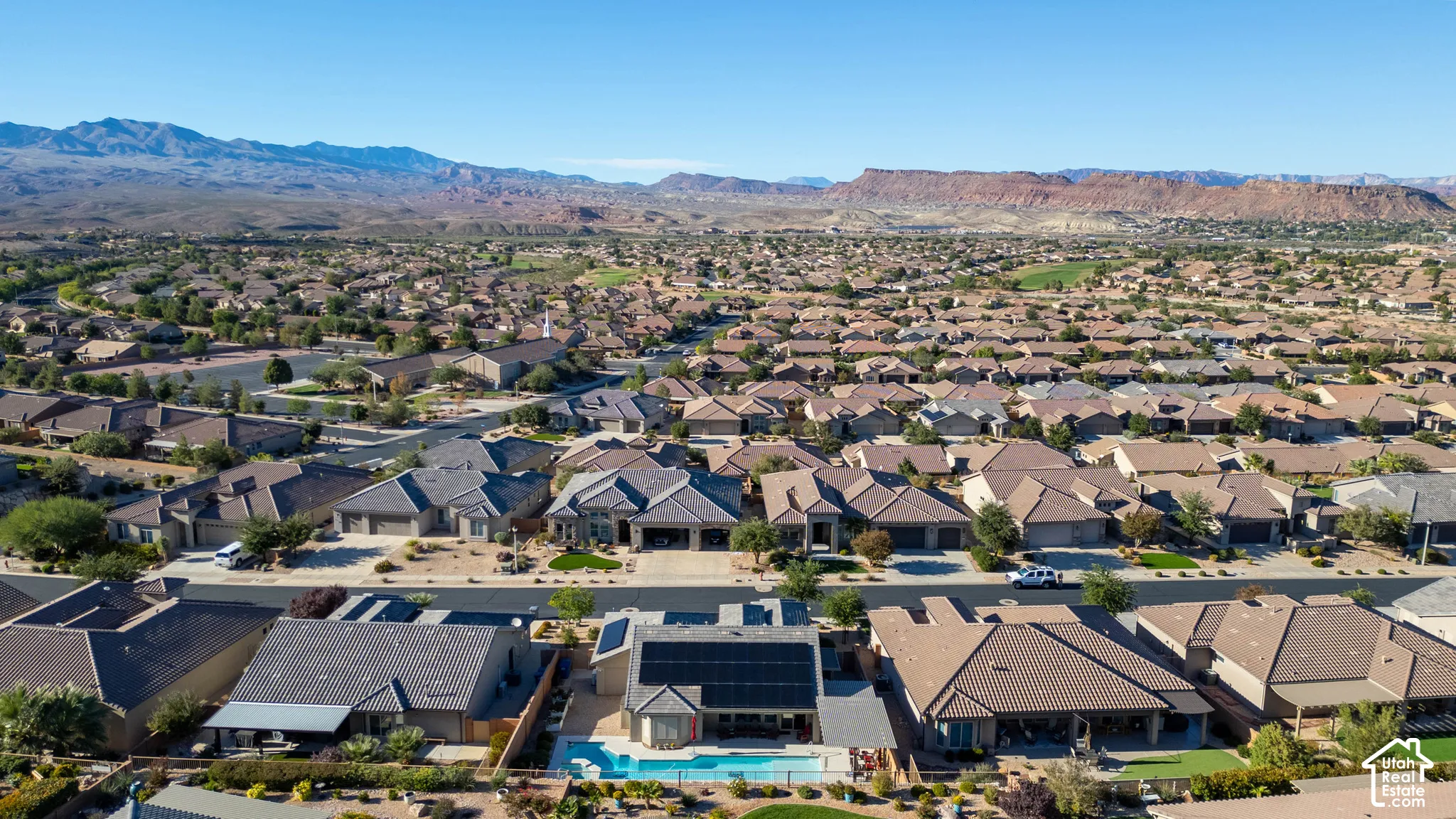 Aerial perspective featuring a property with a private in-ground swimming pool, rooftop solar panels, and a mountain landscape backdrop