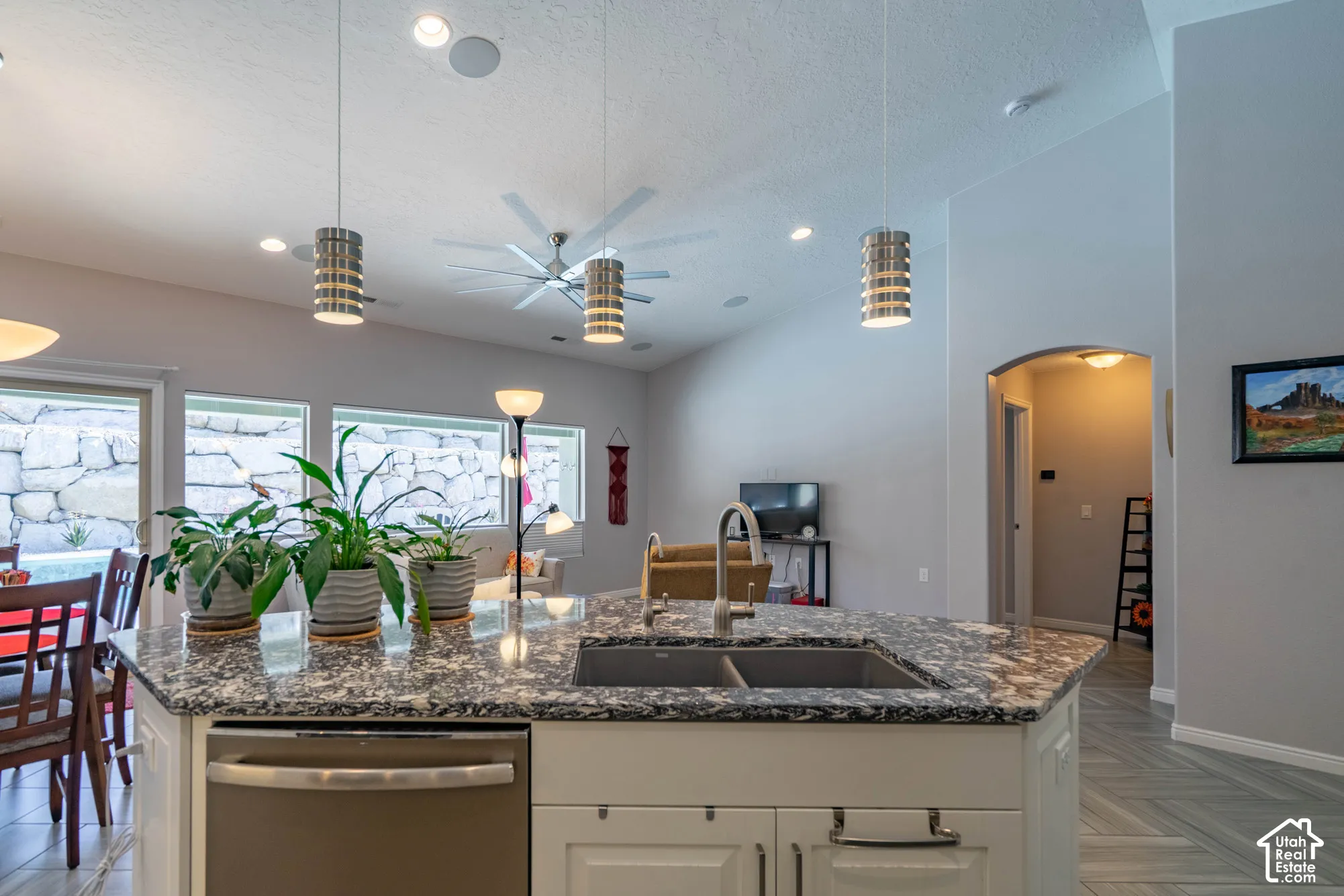 Kitchen island featuring stone-surface countertops, a double-basin undermount sink, recessed lighting, and three cylindrical pendant lights