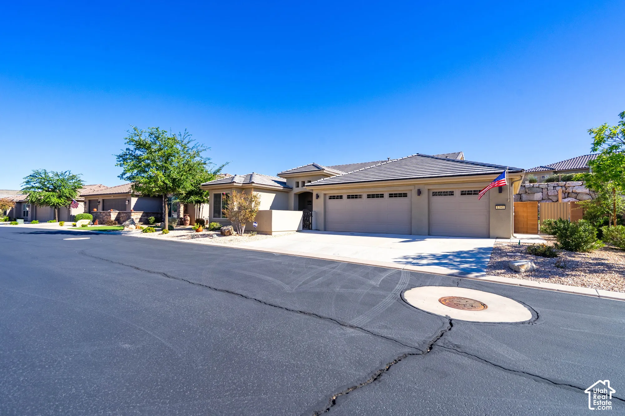 Stucco exterior featuring a tile roof, an attached three-car garage, and concrete driveway