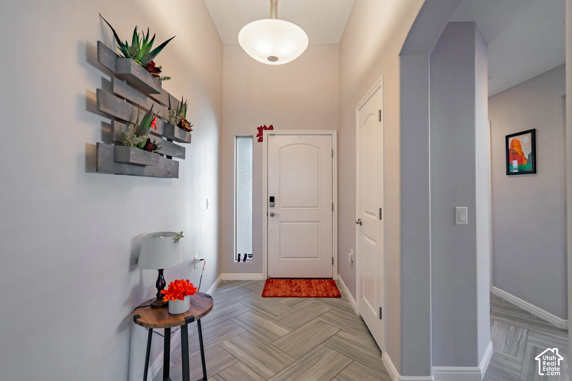 Entryway featuring high ceilings, herringbone-patterned flooring, a semi-flush mount dome light fixture, a sidelight window, and an arched entry