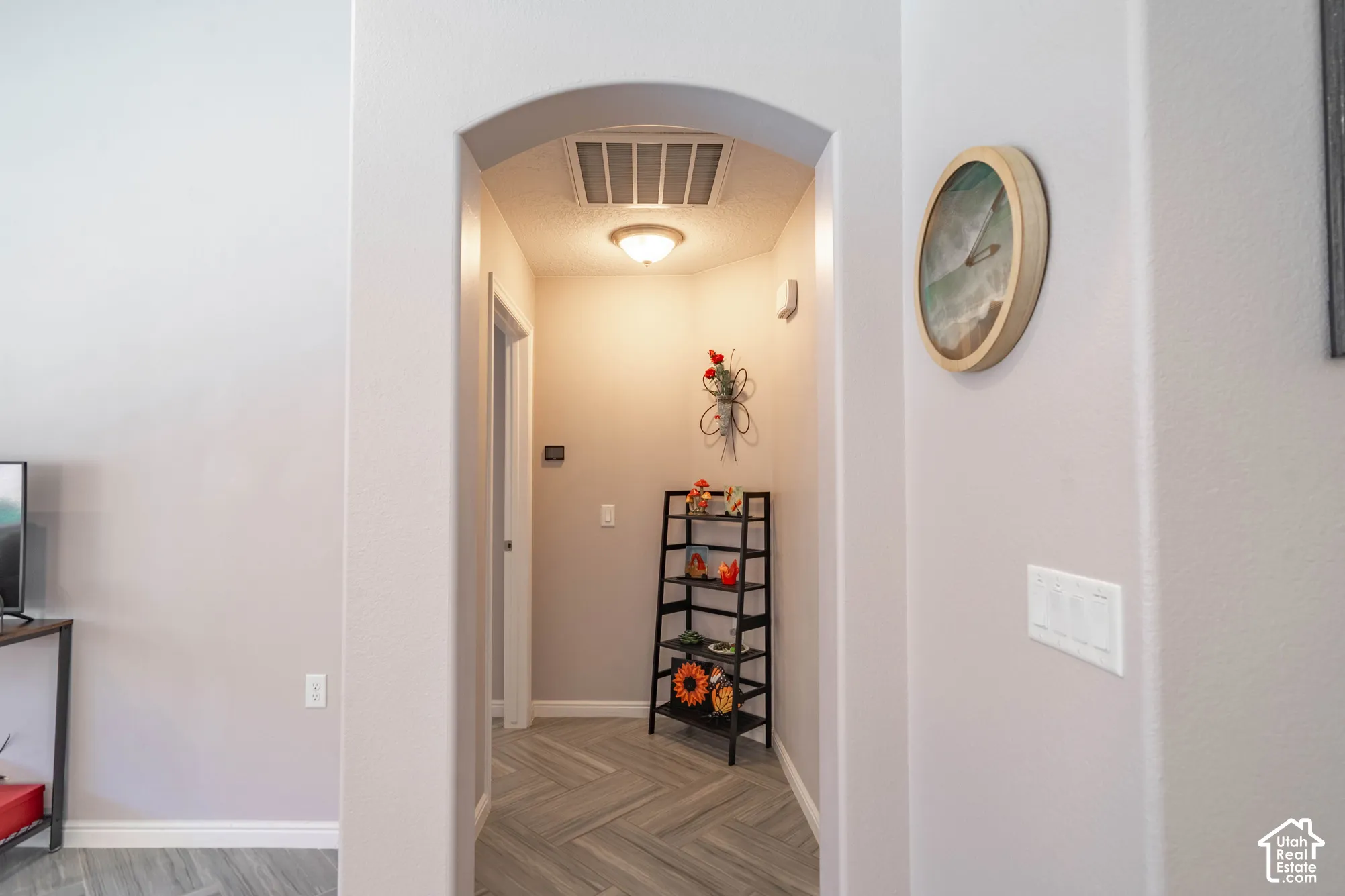 Archway passage featuring wood-finish flooring in a herringbone pattern and a flush-mount ceiling light fixture