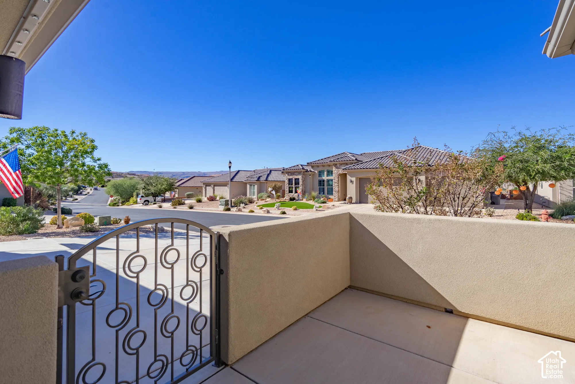 Covered concrete patio featuring a decorative metal gate and stucco privacy walls