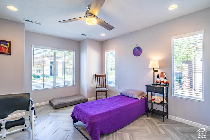 Herringbone-patterned tile flooring, recessed lighting, and a modern ceiling fan in a room with three windows