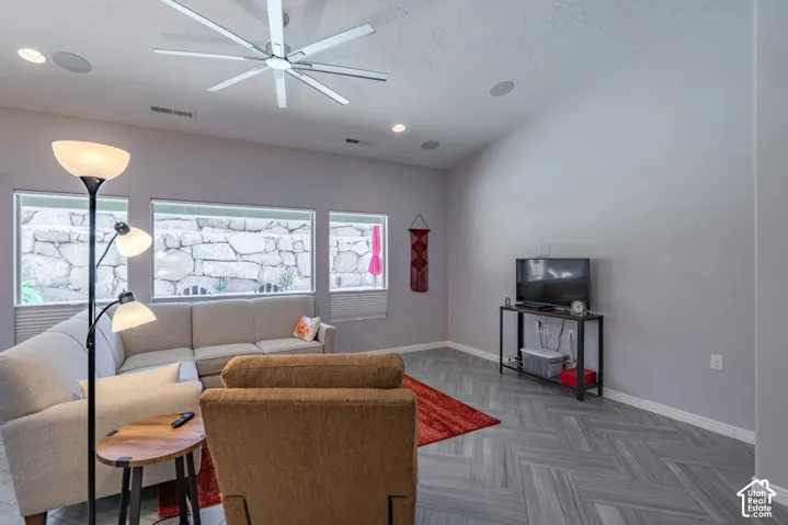 Vaulted ceilings with a multi-blade LED ceiling fan, herringbone-patterned tile flooring, recessed lighting, and expansive windows
