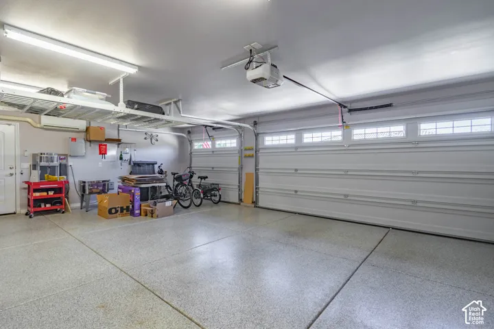 Multi-car garage featuring epoxy-coated flooring, overhead metal storage shelving, integrated ceiling lighting, and sectional garage doors with transom windows