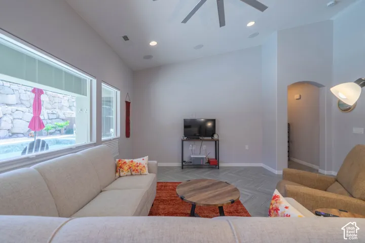 Vaulted ceilings with recessed lighting, chevron-patterned flooring, large picture windows, and a classic arched entryway