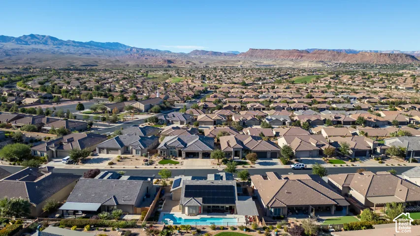Aerial perspective featuring a property with a private in-ground swimming pool, rooftop solar panels, and a mountain landscape backdrop
