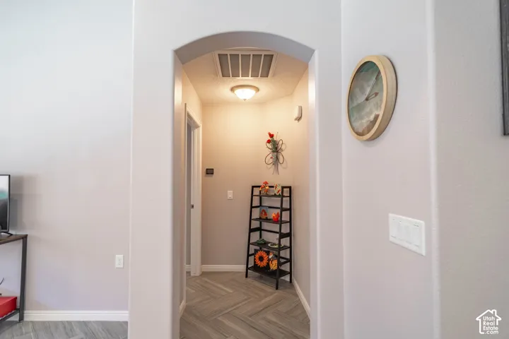 Archway passage featuring wood-finish flooring in a herringbone pattern and a flush-mount ceiling light fixture