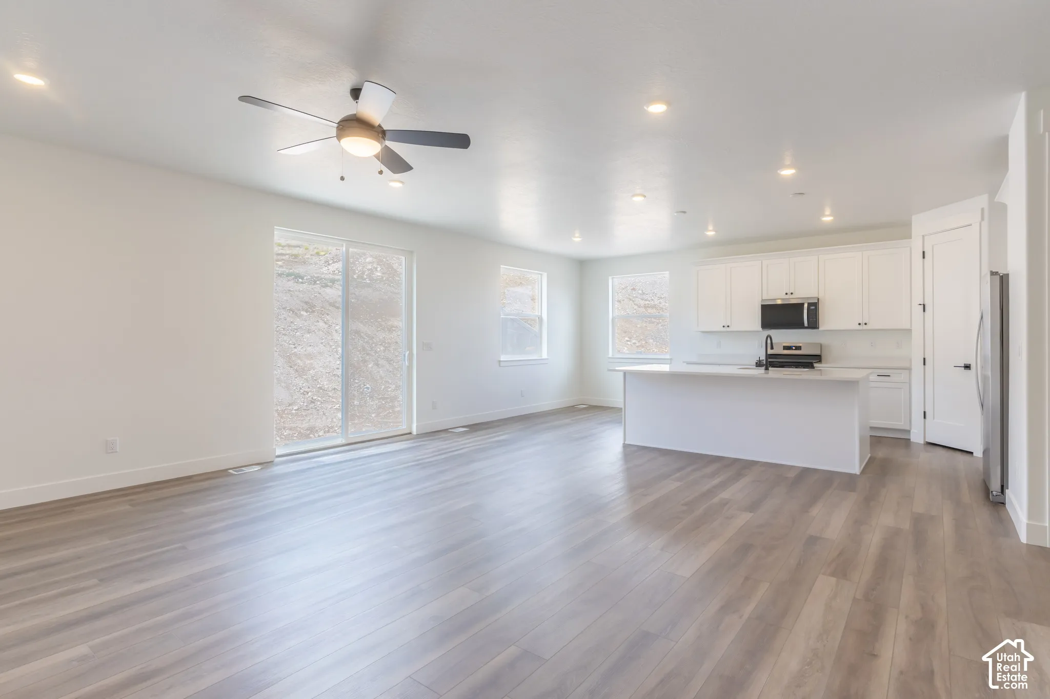 Open-concept kitchen featuring white cabinetry, a center island with a stone-surfaced countertop, and stainless steel appliances