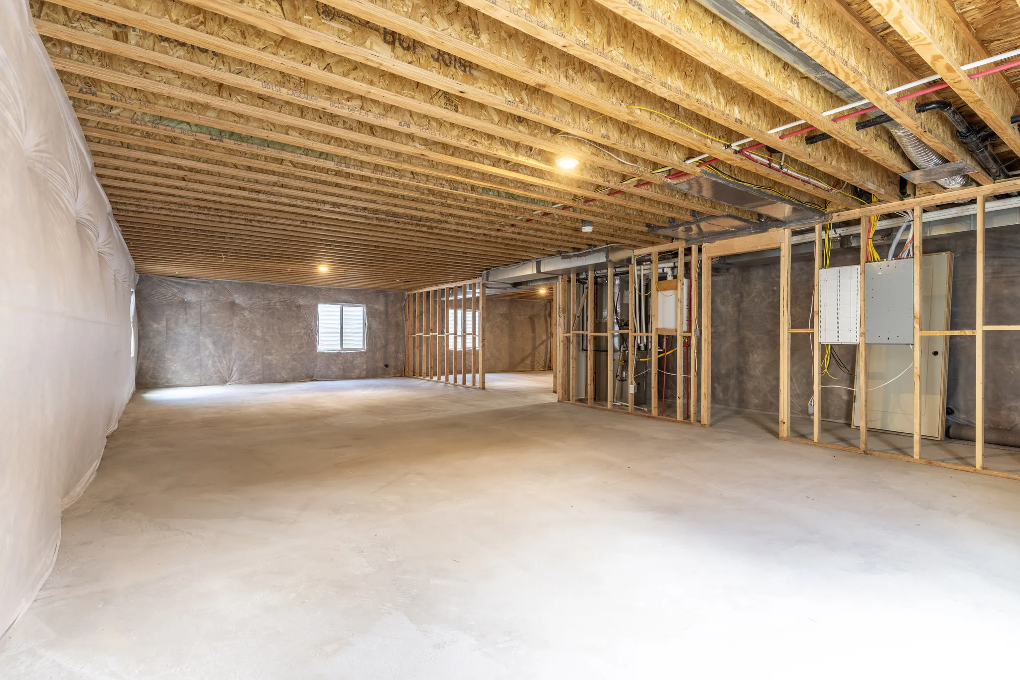 Unfinished lower level featuring exposed wood joist ceilings, concrete flooring, insulated wall barriers, and wooden stud framing