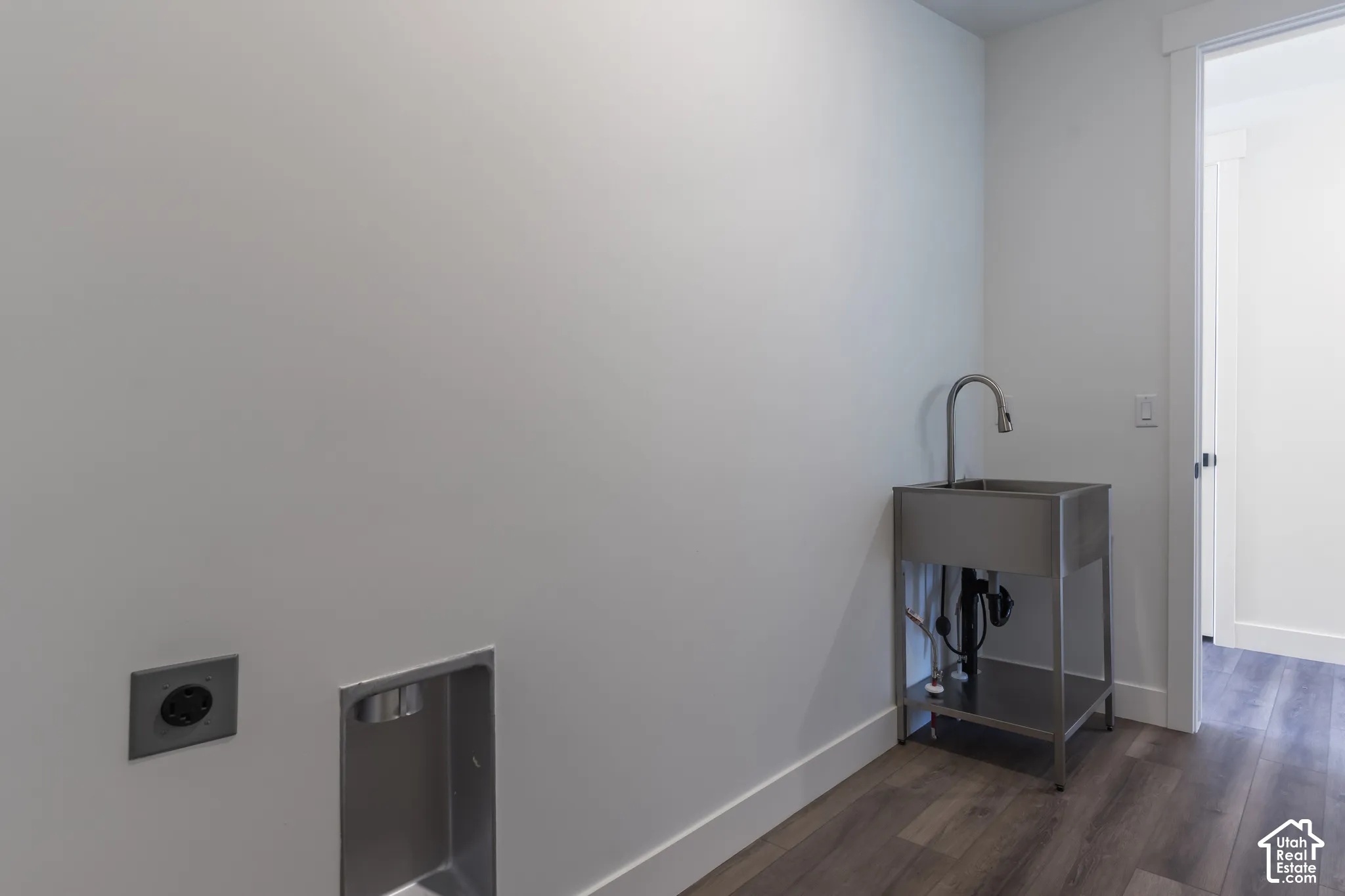 Utility area featuring wood-finish flooring, recessed laundry hookups, and a stainless steel utility sink with a high-arch pull-down faucet