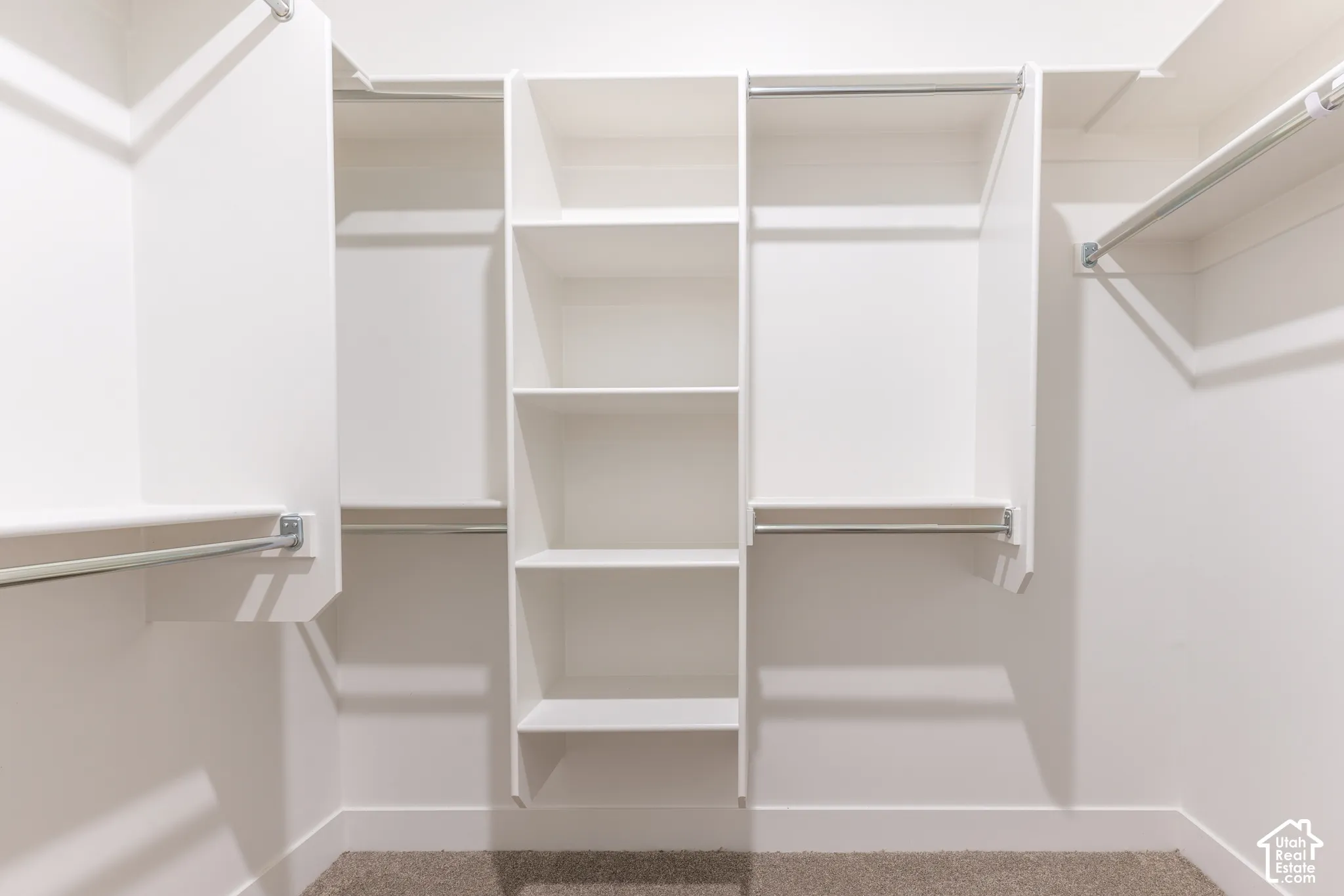Walk-in closet featuring white built-in shelving, multi-level clothing rods, and wall-to-wall carpeting