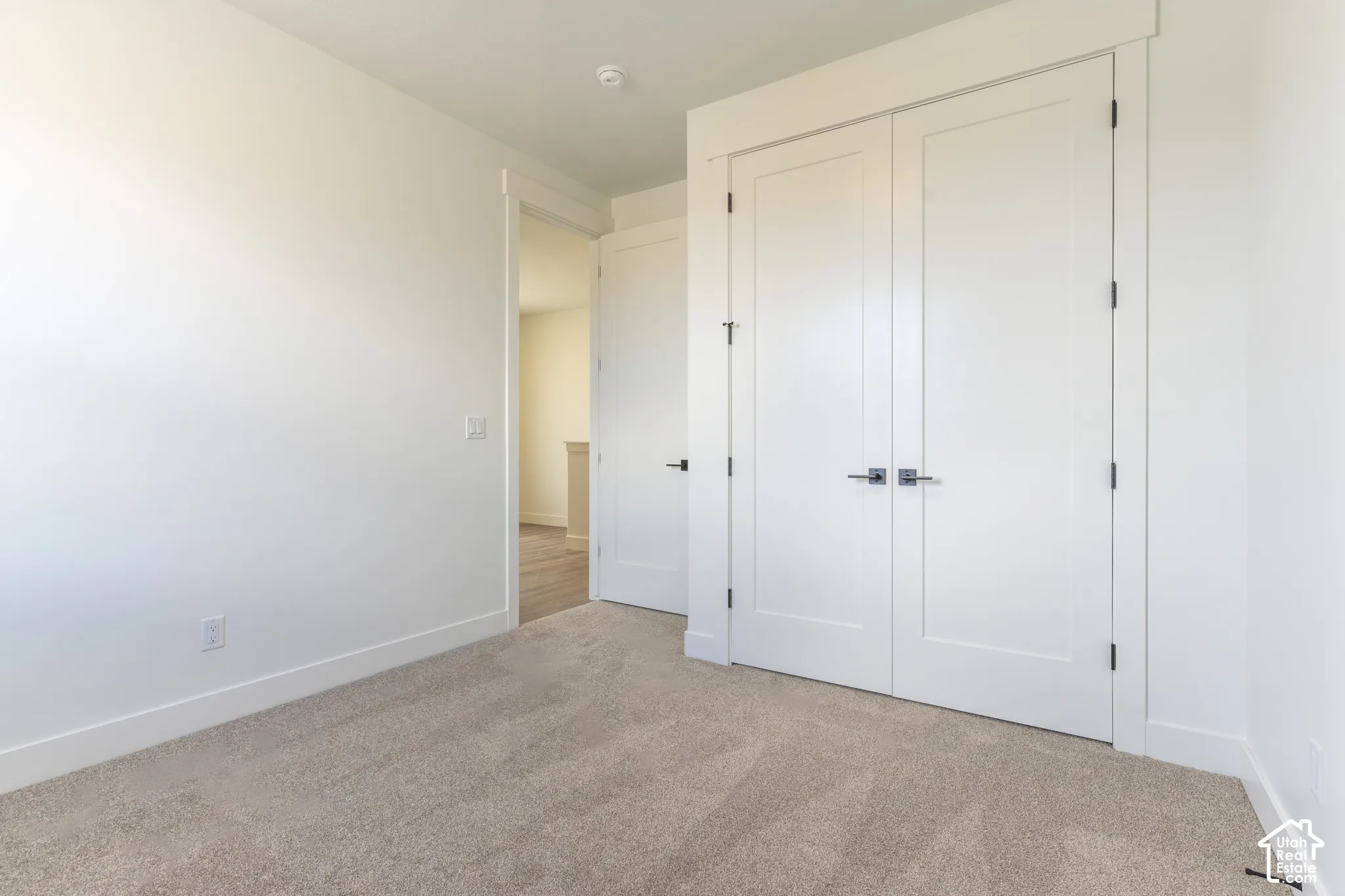 Neutral-toned wall-to-wall carpeting, white shaker-style interior doors, and matte black hardware