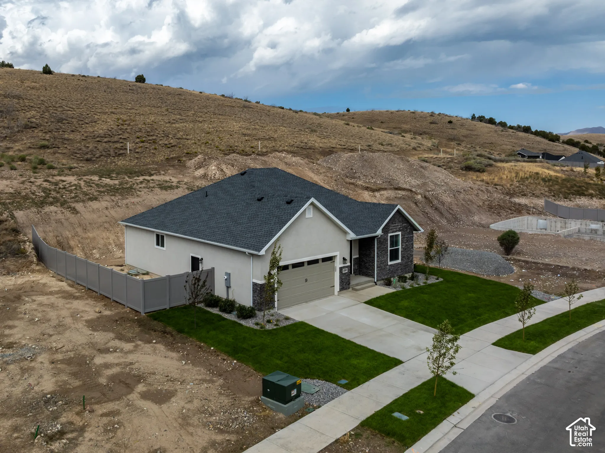 Single-level residence featuring a composite shingle roof, stone veneer accents, attached two-car garage, concrete driveway, and side privacy fencing