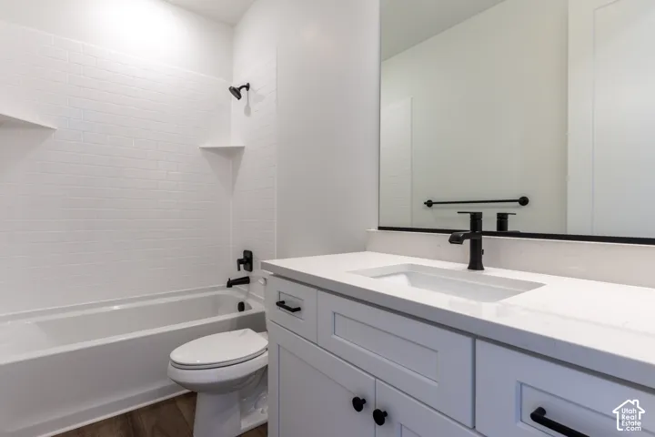 Bathroom featuring a white shaker-style vanity with quartz countertop, undermount sink, matte black hardware, and a subway-tiled tub surround