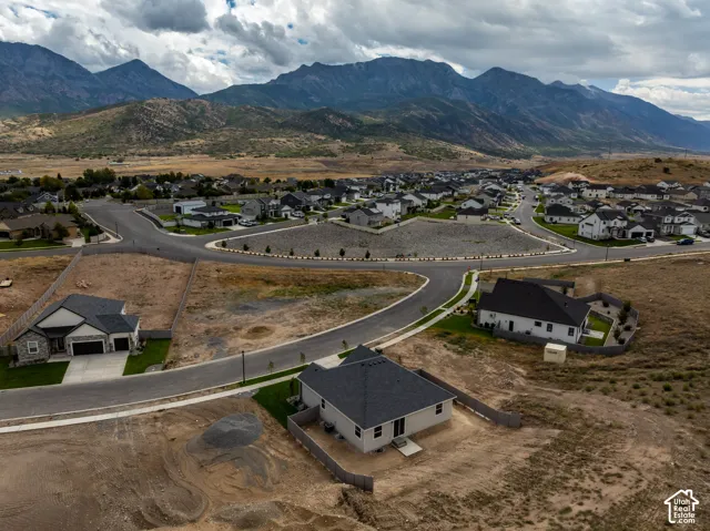 Aerial perspective of the property featuring a suburban residential setting, paved asphalt streets, concrete sidewalks, and an expansive mountain range backdrop