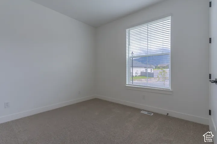 Neutral-toned carpeted flooring, white wall finishes, and a single-pane window equipped with horizontal blinds