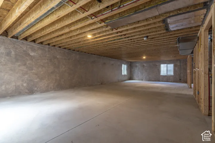 Unfinished interior space featuring exposed wood joist ceilings, poured concrete flooring, concrete foundation walls, and framed interior partition walls