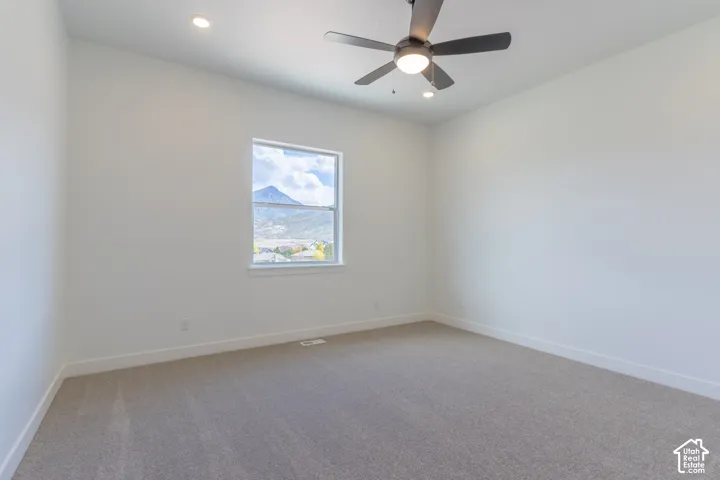 Interior space featuring high ceilings, neutral wall-to-wall carpeting, recessed lighting, and a ceiling fan with integrated light fixture, complemented by a window showcasing mountain scenery