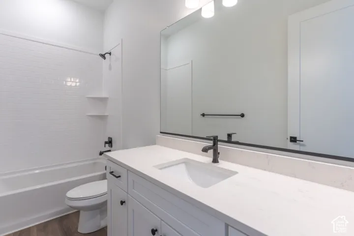 Bathroom featuring a white vanity with a light-toned stone countertop, large wall-mounted mirror, white subway tile shower surround, and matte black fixtures