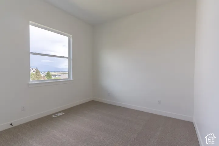Neutral interior space featuring high ceilings, wall-to-wall carpeting, and a window with mountain scenery