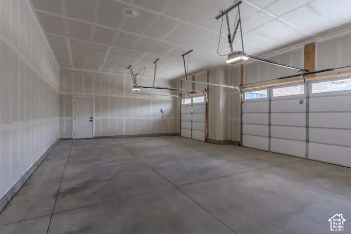 Three-car garage featuring a concrete floor, finished drywall, and two automated garage door openers