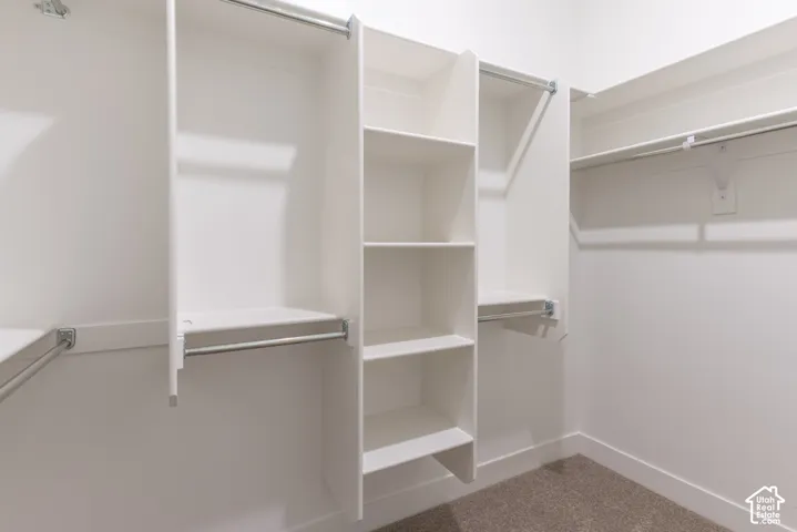 Walk-in closet featuring white built-in shelving, vertical storage partitions, and dual-level hanging rods