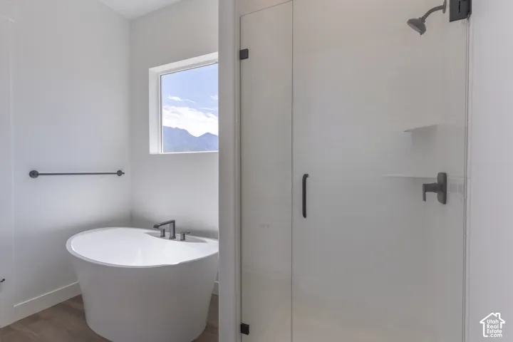 Freestanding soaking tub with a deck-mounted faucet, walk-in glass-enclosed shower featuring matte black hardware, and mountain scenery