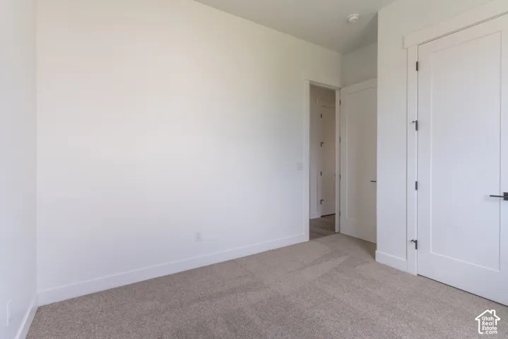 Neutral-toned wall-to-wall carpeting, clean white walls, and interior doors featuring matte black hardware and Shaker-style panels