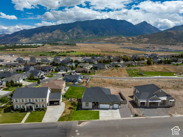Aerial view of single-family residences featuring multi-car garages, asphalt shingle roofing, concrete driveways, and expansive mountain backdrops