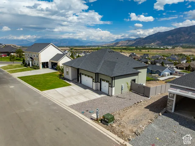 Single-story residence featuring a two-car garage, stone and siding exterior, concrete driveway, and mountain backdrop