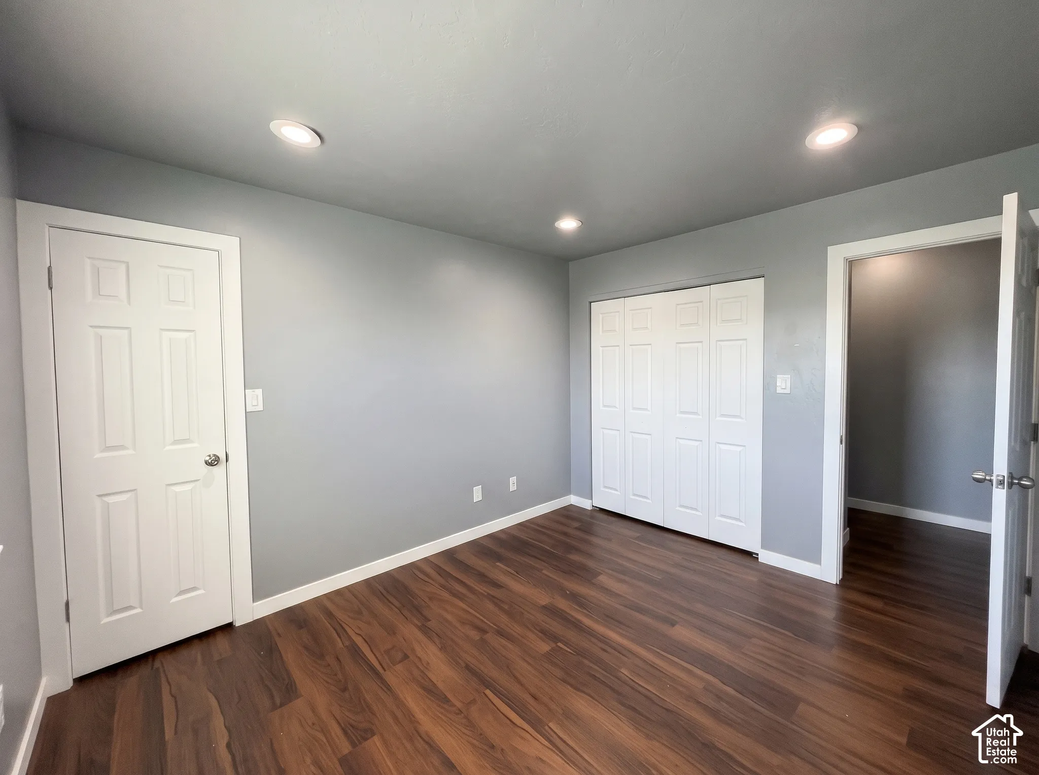 Room with wood-finish flooring, recessed lighting, and white six-panel interior doors, including a bifold closet door