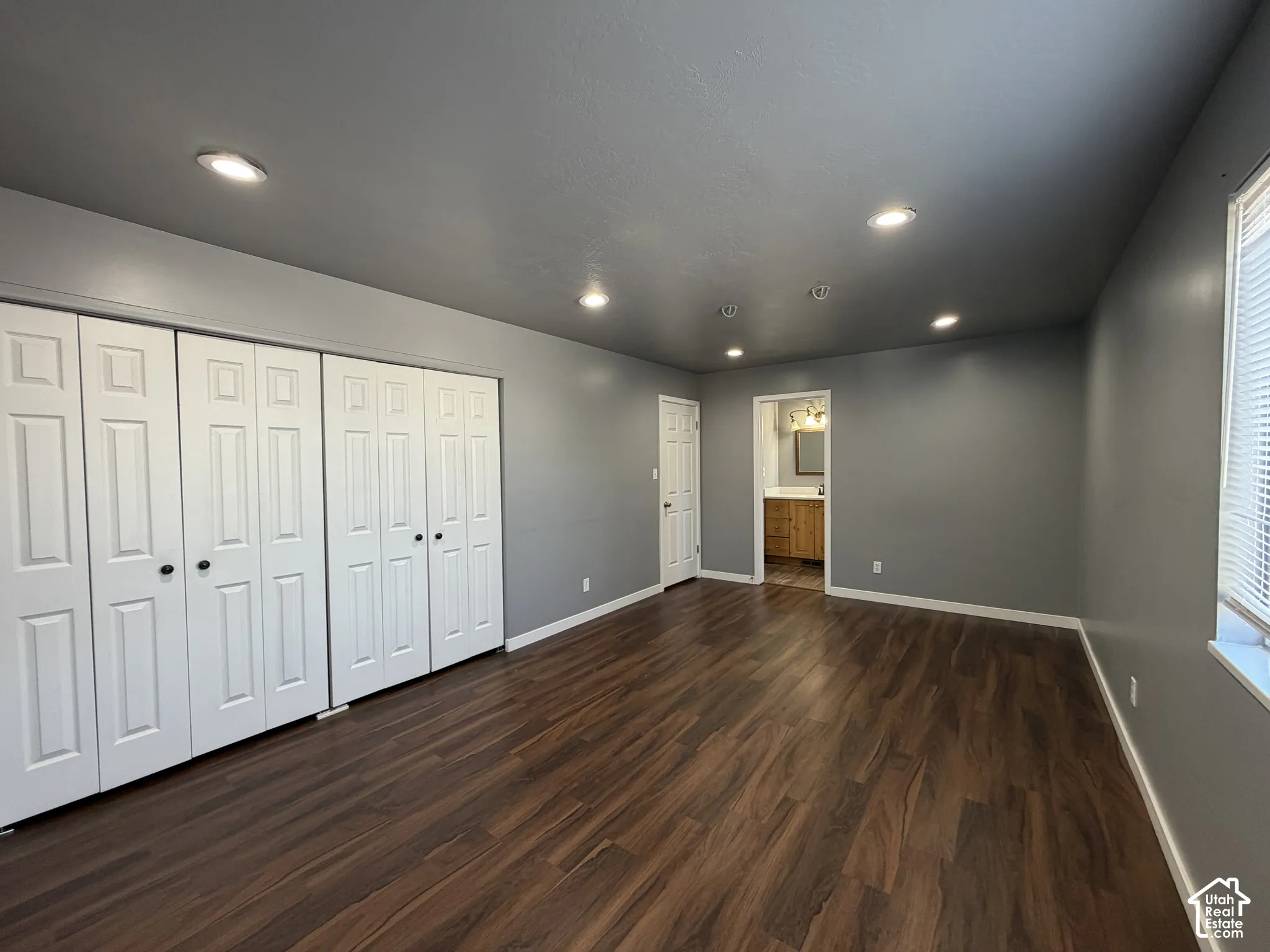 Room featuring wood-finish flooring, recessed lighting, and built-in closet cabinetry with panel doors