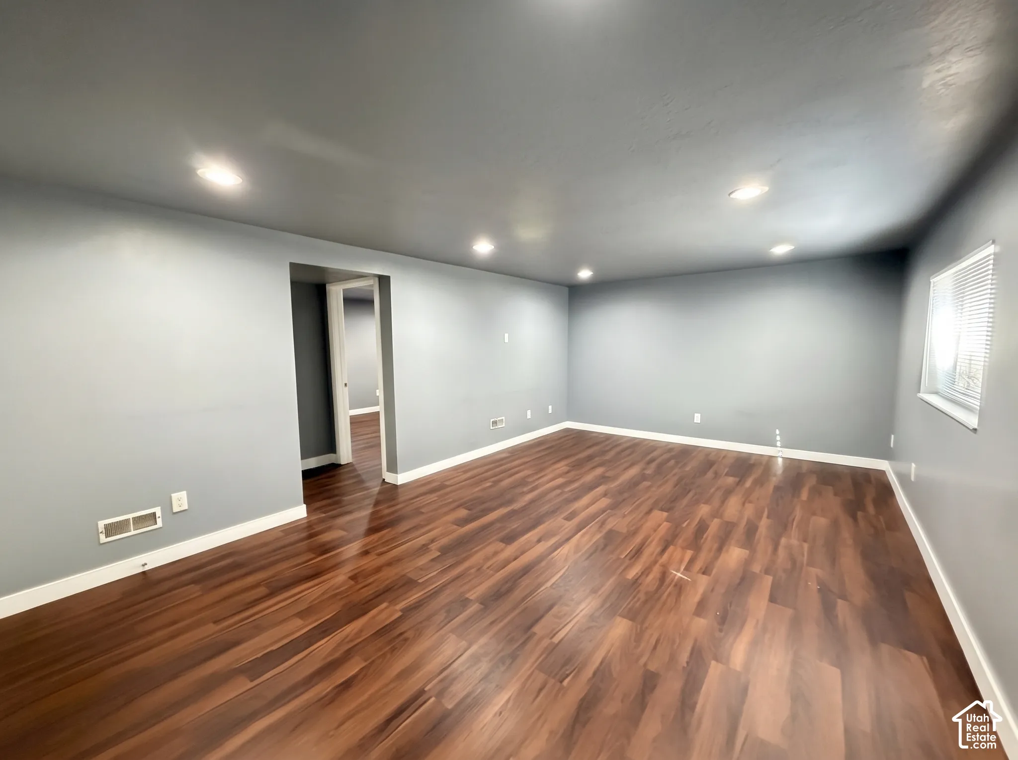 Spacious room featuring wood-finish flooring, recessed lighting, and neutral wall tones