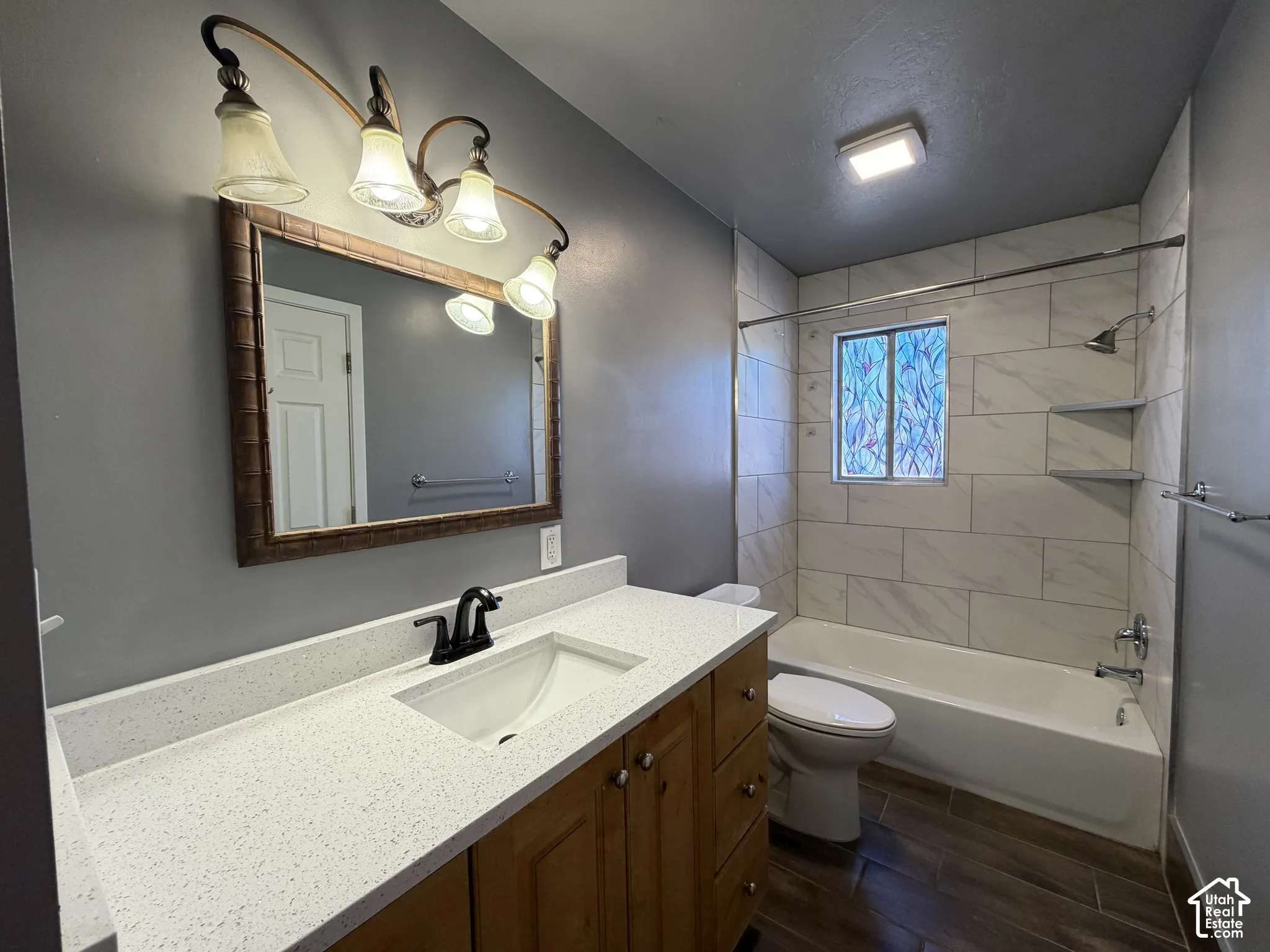 Bathroom featuring a vanity with a light-toned countertop, integrated basin, matte black faucet, and wood-finish cabinetry