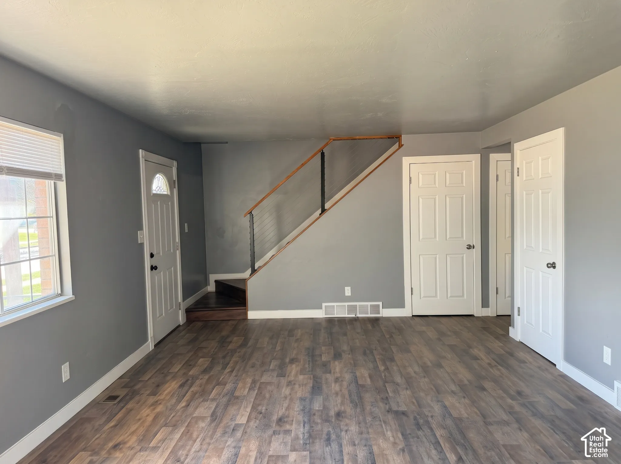 Interior space featuring wood-finish flooring, staircase with a wood handrail and cable railing, and three six-panel interior doors